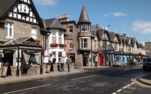 Street view of traditional stone buildings and shops in Pitlochry, Scotland.