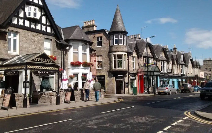 Street view of traditional stone buildings and shops in Pitlochry, Scotland.