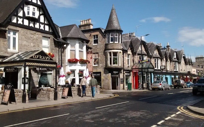 Street view of traditional stone buildings and shops in Pitlochry, Scotland.