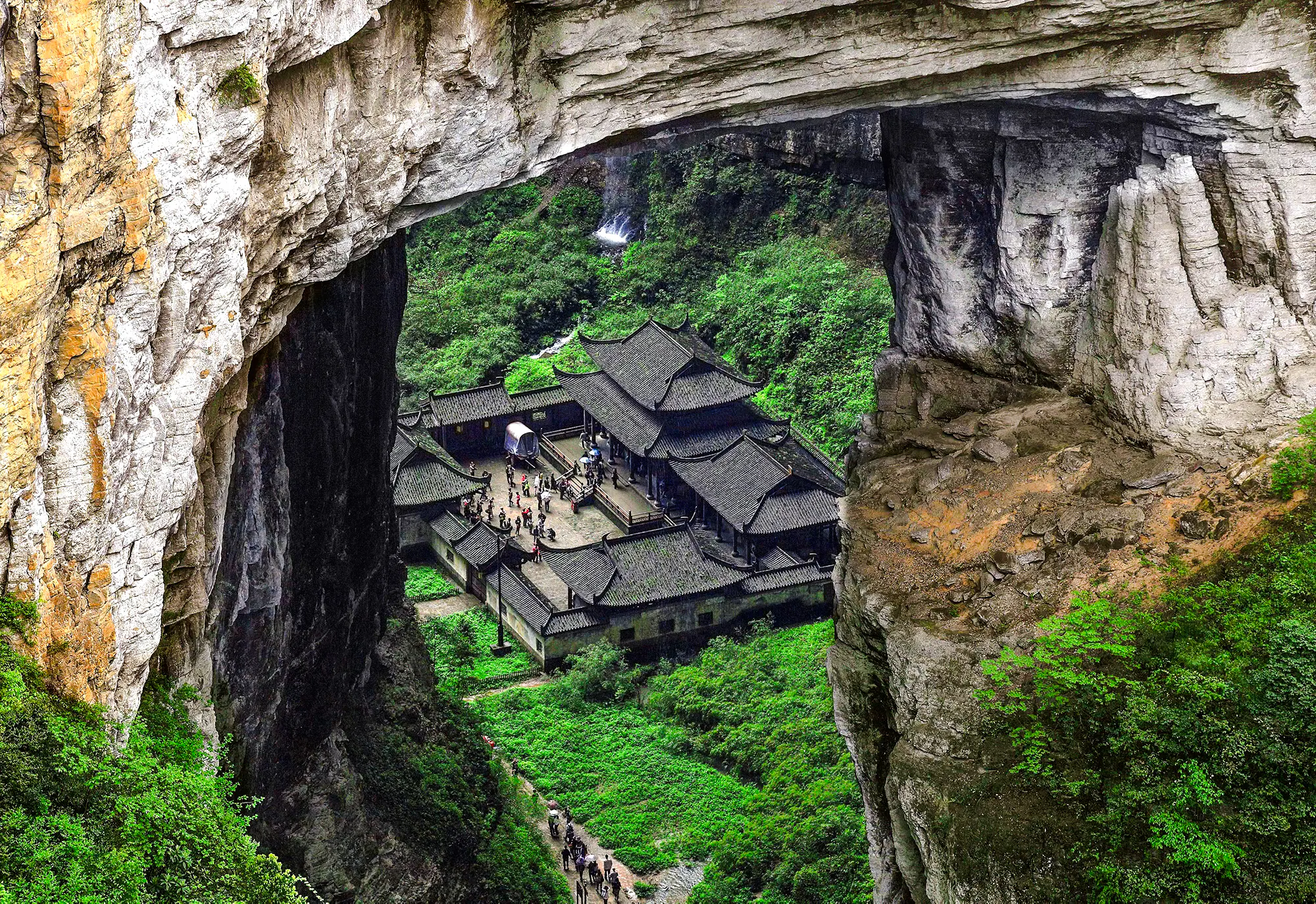 Wulong Three Natural Bridges with traditional buildings in lush gorge, Chongqing day tour.