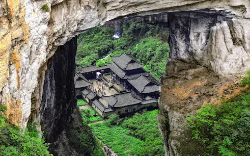 Wulong Three Natural Bridges with traditional buildings in lush gorge, Chongqing day tour.