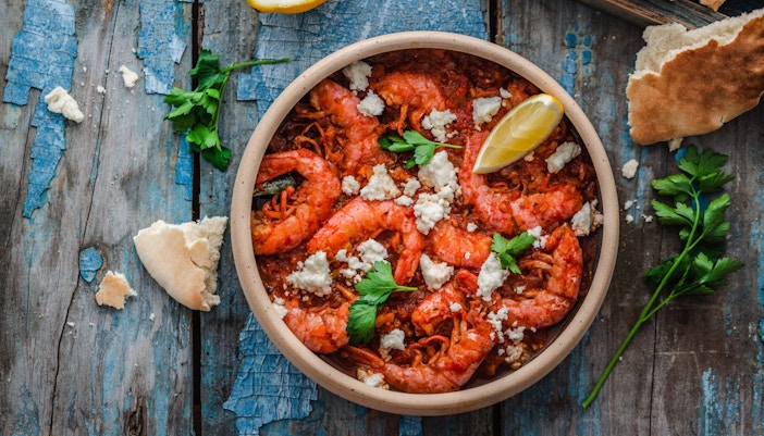 Garides saganaki with shrimp, feta, and lemon on a rustic table in Athens.
