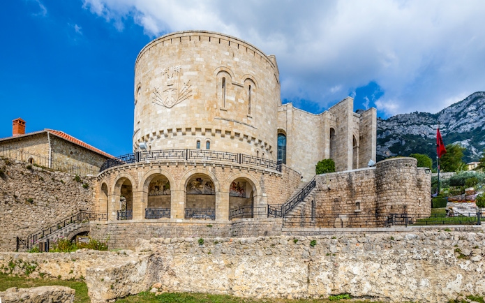 Kruje Castle with stone walls and Albanian flag, Kruje, Albania.
