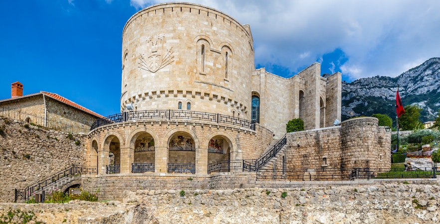 Kruje Castle with stone walls and Albanian flag, Kruje, Albania.