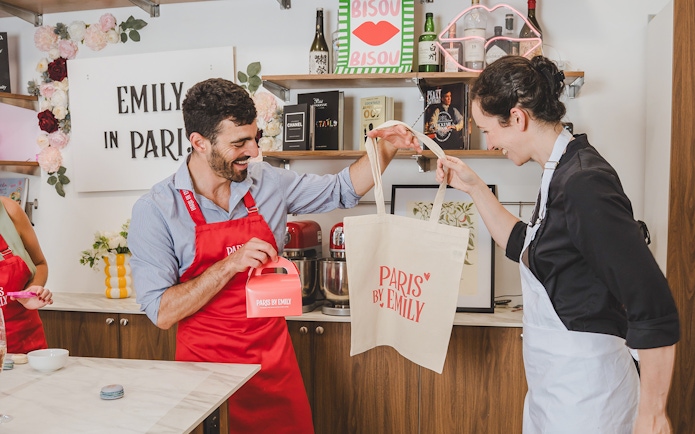 Participants enjoying a macaron-making workshop in Paris, holding branded bags and boxes.