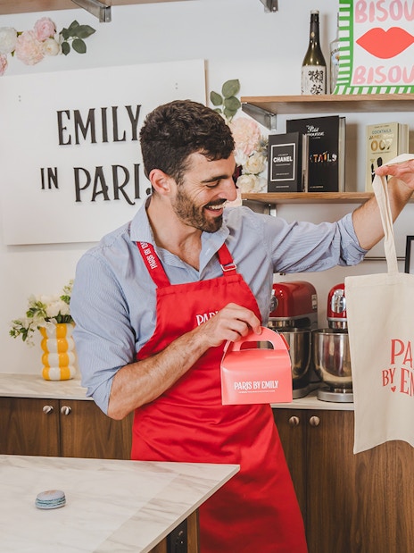 Participants enjoying a macaron-making workshop in Paris, holding branded bags and boxes.