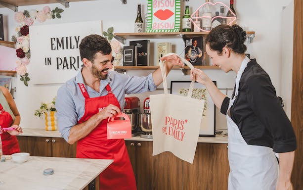 Participants enjoying a macaron-making workshop in Paris, holding branded bags and boxes.