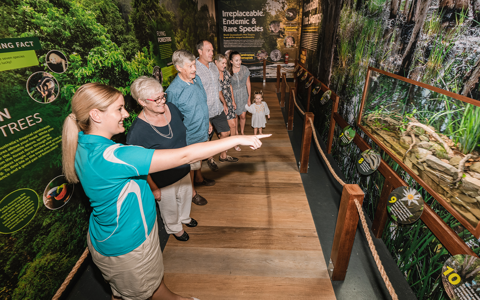 Visitors touring Cairns Aquarium exhibit with guide pointing at display.