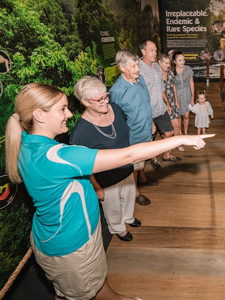 Visitors touring Cairns Aquarium exhibit with guide pointing at display.