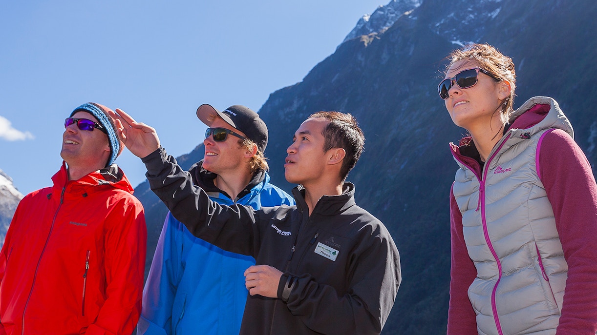 Tourists enjoying a guided tour at Milford Sound with scenic fjord backdrop.