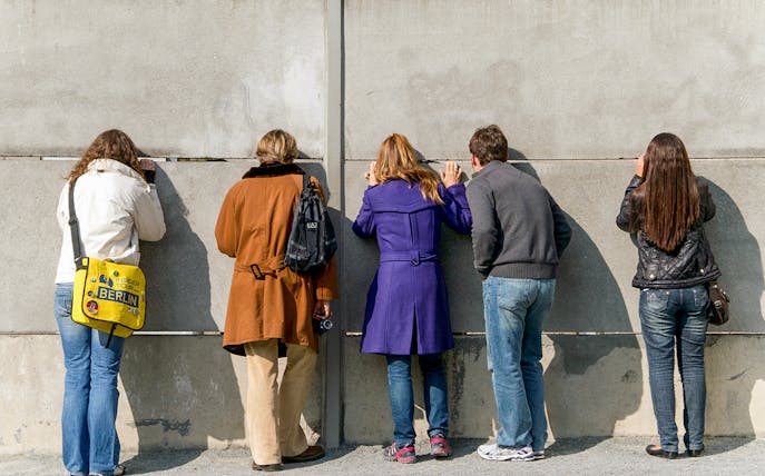 People peering through a gap in the Berlin Wall on the Mauer Tour.