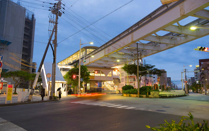 Okinawa Monorail station entrance at dusk with street view.