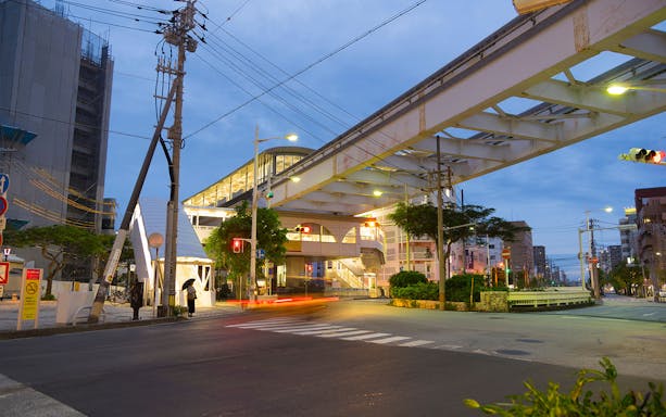 Okinawa Monorail station entrance at dusk with street view.