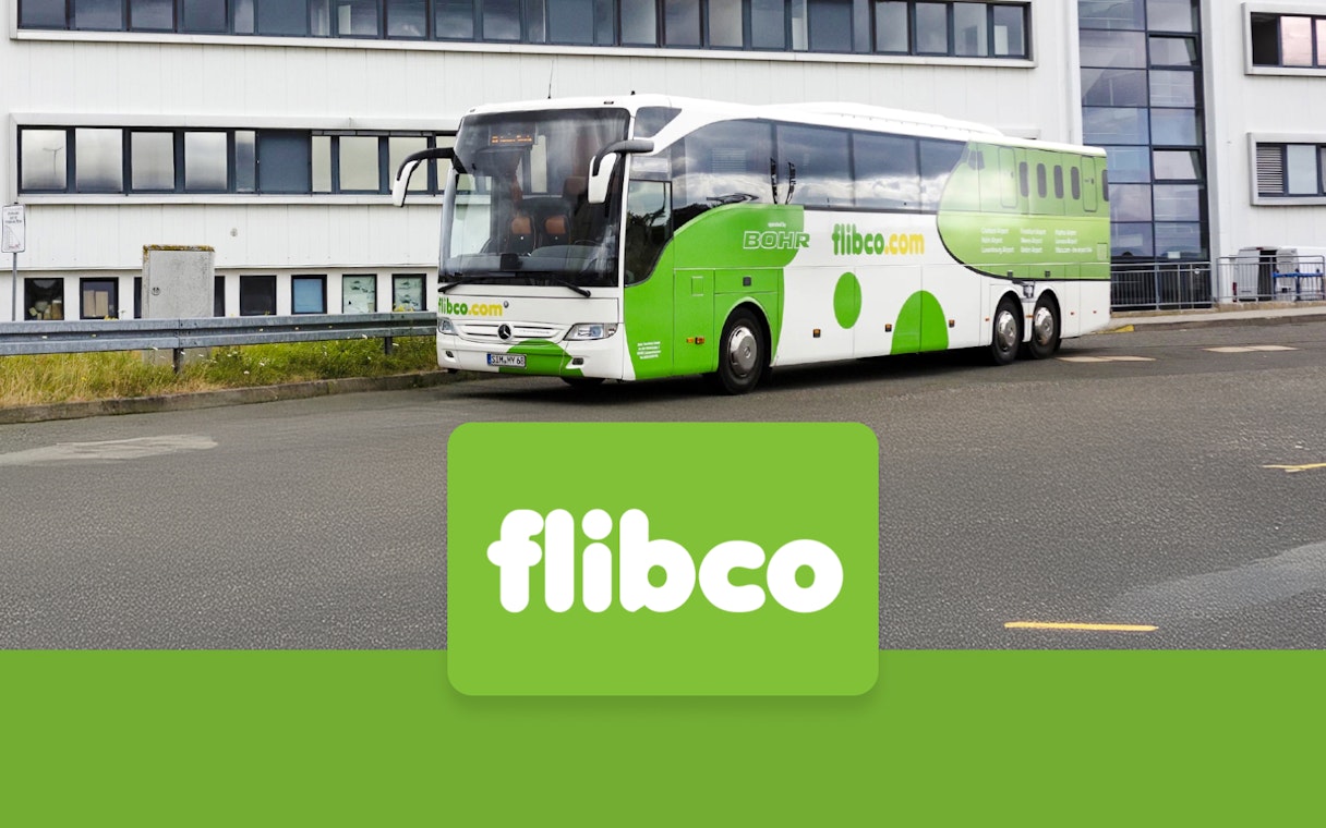 Flibco bus parked near a building, offering transfers between London Stansted Airport and London City.