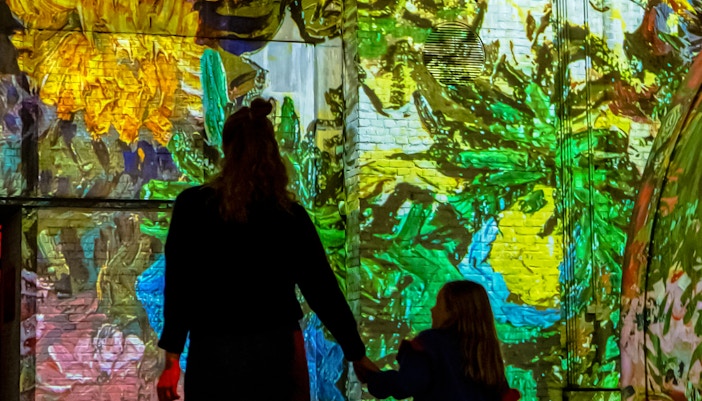 Visitors enjoying immersive art projections at Fabrique des Lumières.