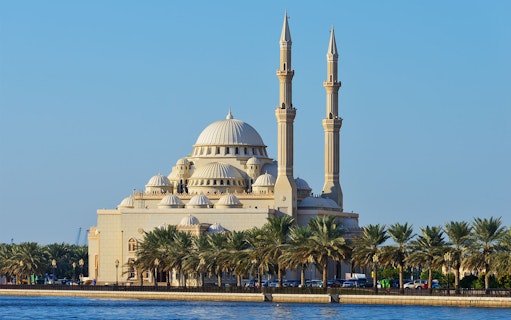 Sharjah Mosque with palm trees along the waterfront on the Hop-On-Hop-Off Bus Tour.