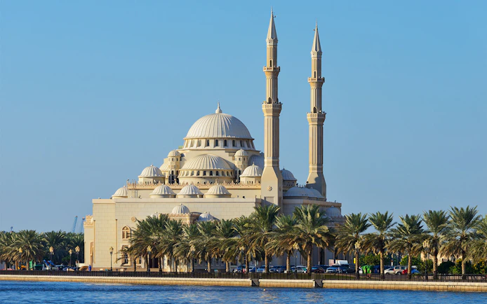 Sharjah Mosque with palm trees along the waterfront on the Hop-On-Hop-Off Bus Tour.