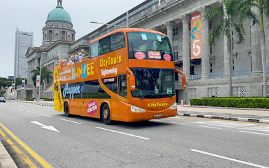 Open-top FunVee bus on a city tour in Singapore passing historic buildings.