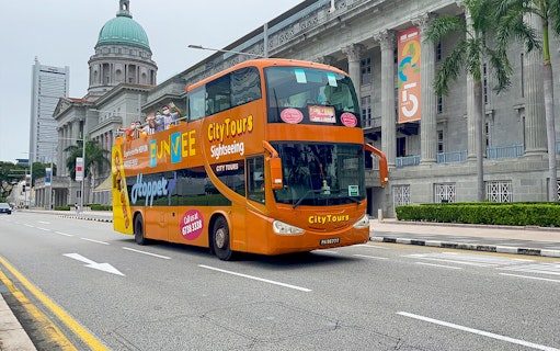 Open-top FunVee bus on a city tour in Singapore passing historic buildings.