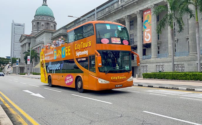Open-top FunVee bus on a city tour in Singapore passing historic buildings.