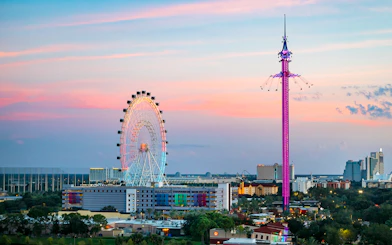 Ferris wheel and swing ride at sunset in Orlando amusement park.