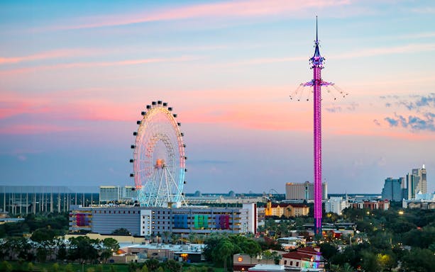 Ferris wheel and swing ride at sunset in Orlando amusement park.