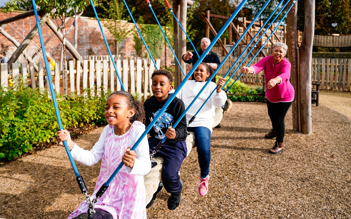 Children playing on swings at the adventure play area in Blenheim Palace.