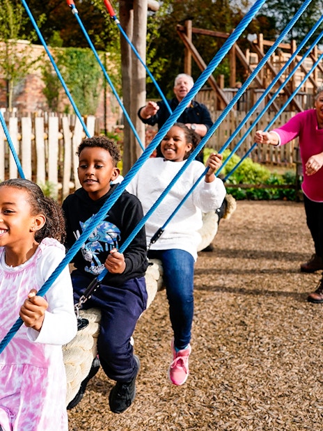 Children playing on swings at the adventure play area in Blenheim Palace.