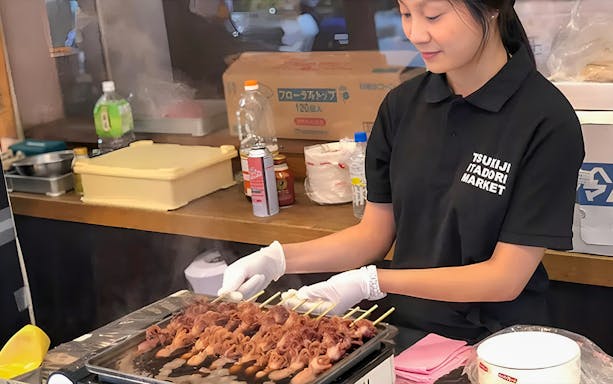 Vendor grilling skewers at Tsukiji Itadori Market, Tokyo, during private sightseeing tour.