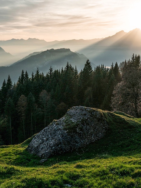 Mount Rigi landscape with sun rays over forested hills and distant mountains.