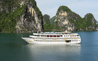 Starlight Cruise sailing in Halong Bay with limestone cliffs in the background.