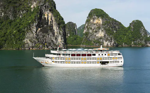 Starlight Cruise sailing in Halong Bay with limestone cliffs in the background.