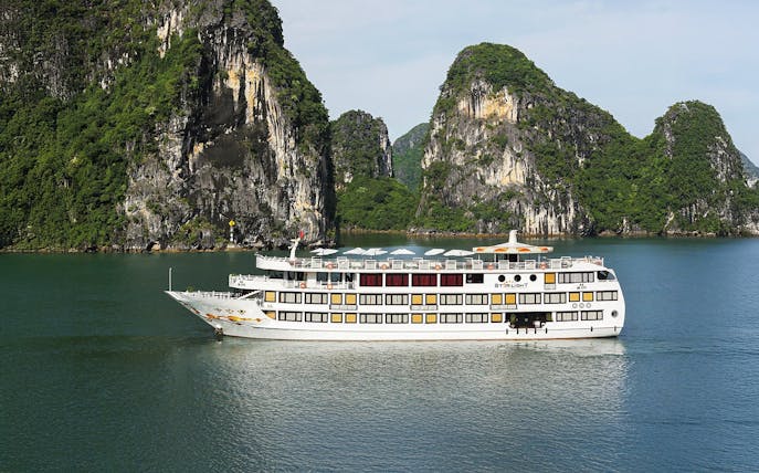 Starlight Cruise sailing in Halong Bay with limestone cliffs in the background.