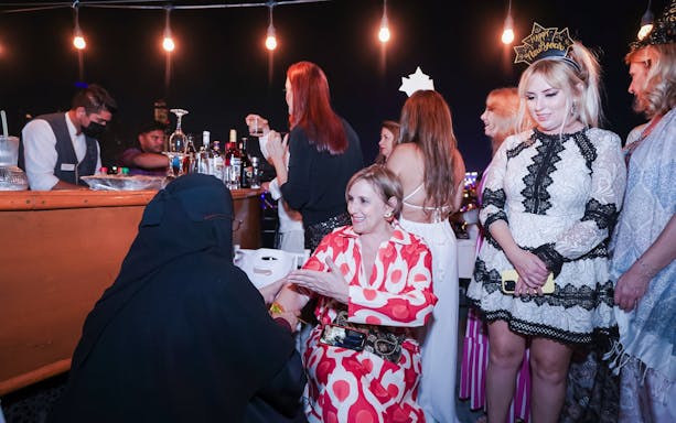 Guests enjoying New Year's Eve Marina Dhow Dinner Cruise with drinks and festive attire.