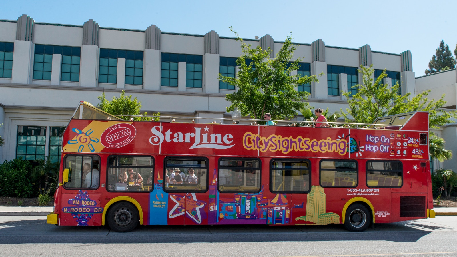 Ein Los Angeles Hop-on Hop-off Bus des Anbieters City Sightseeing fährt an einem Gebäude vorbei