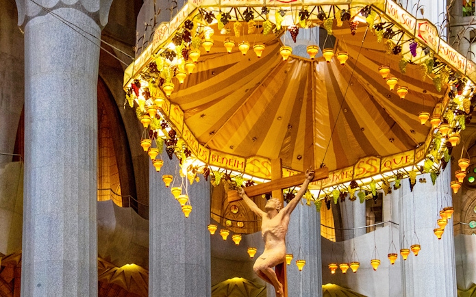 Sagrada Familia interior with crucifix and ornate canopy during guided tour.