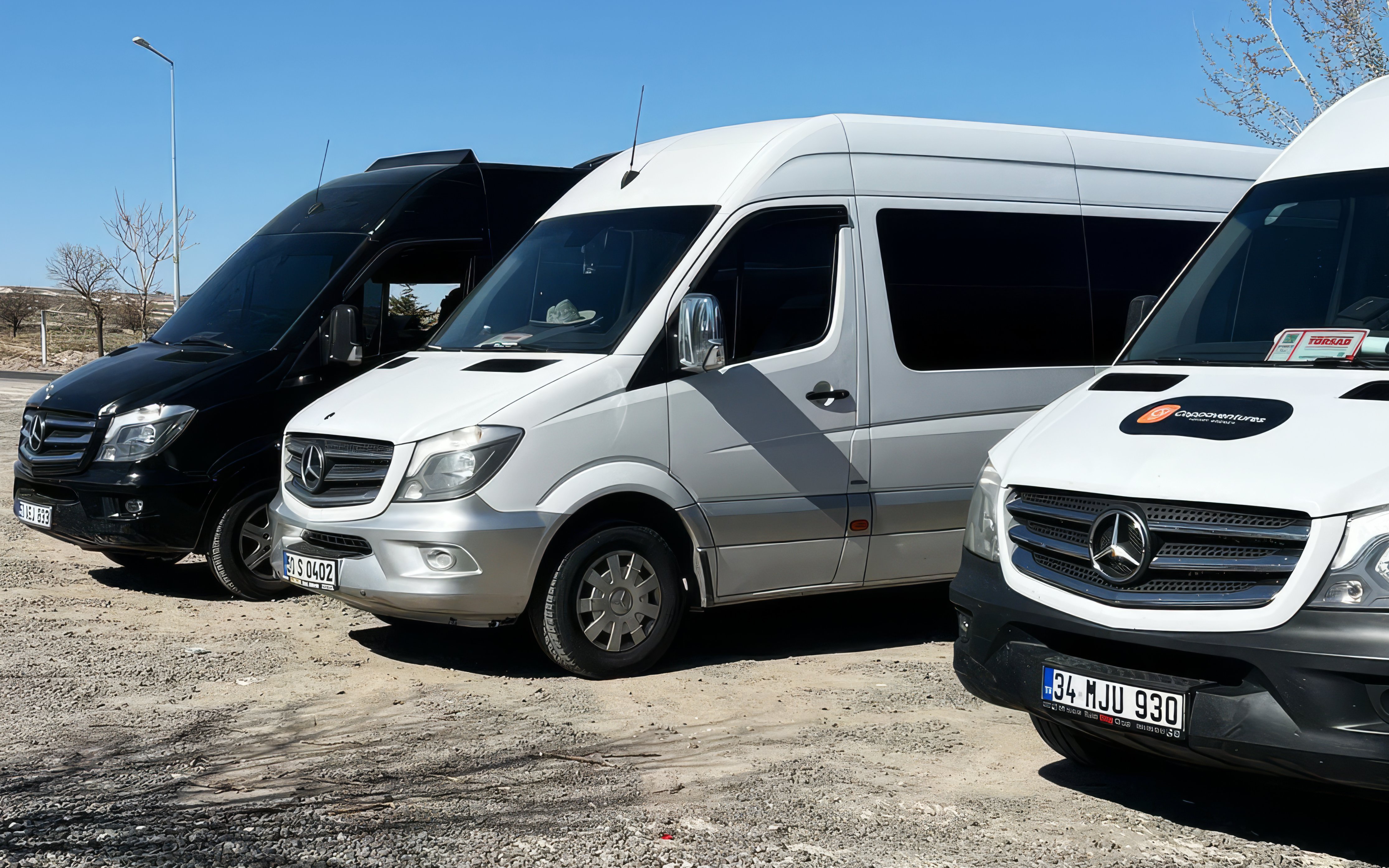 Hotel transfer vans parked in a lot under a clear blue sky.
