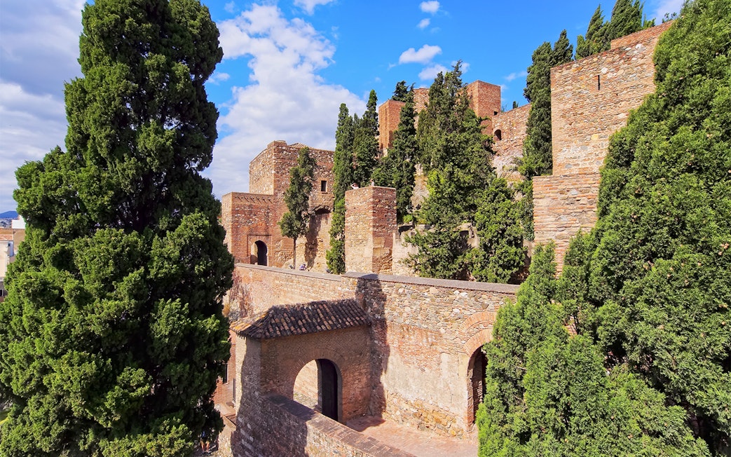 Roman Theater and Alcazaba Castle walls surrounded by lush greenery in Málaga, Spain.