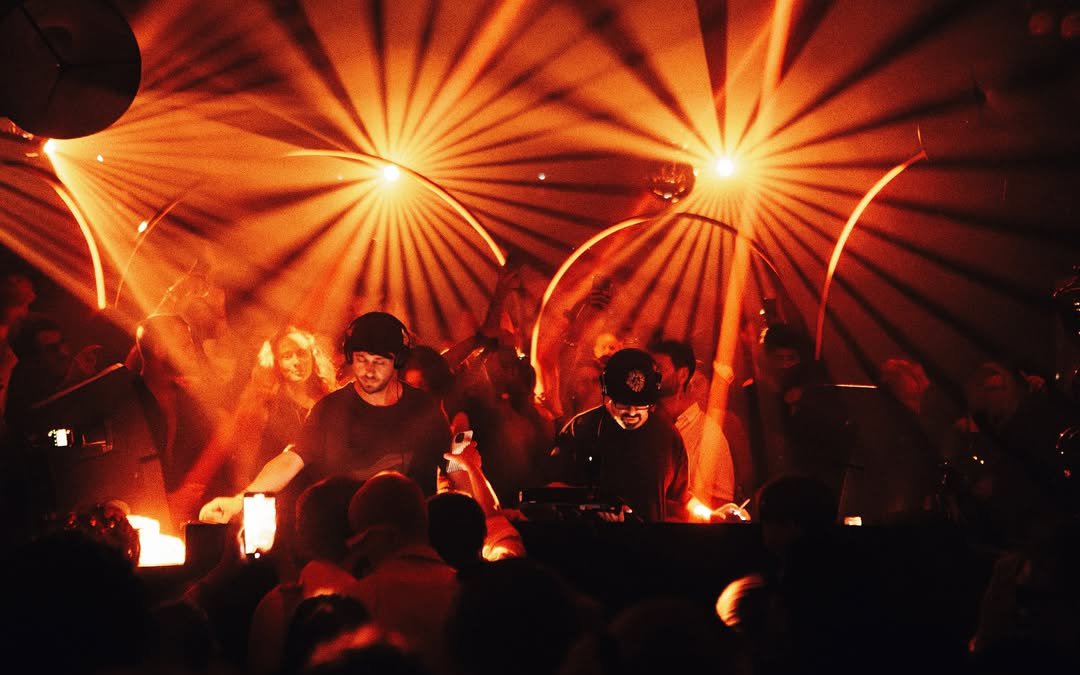 DJ performing at Club Chinois, Ibiza with vibrant lights and crowd on Sunday.