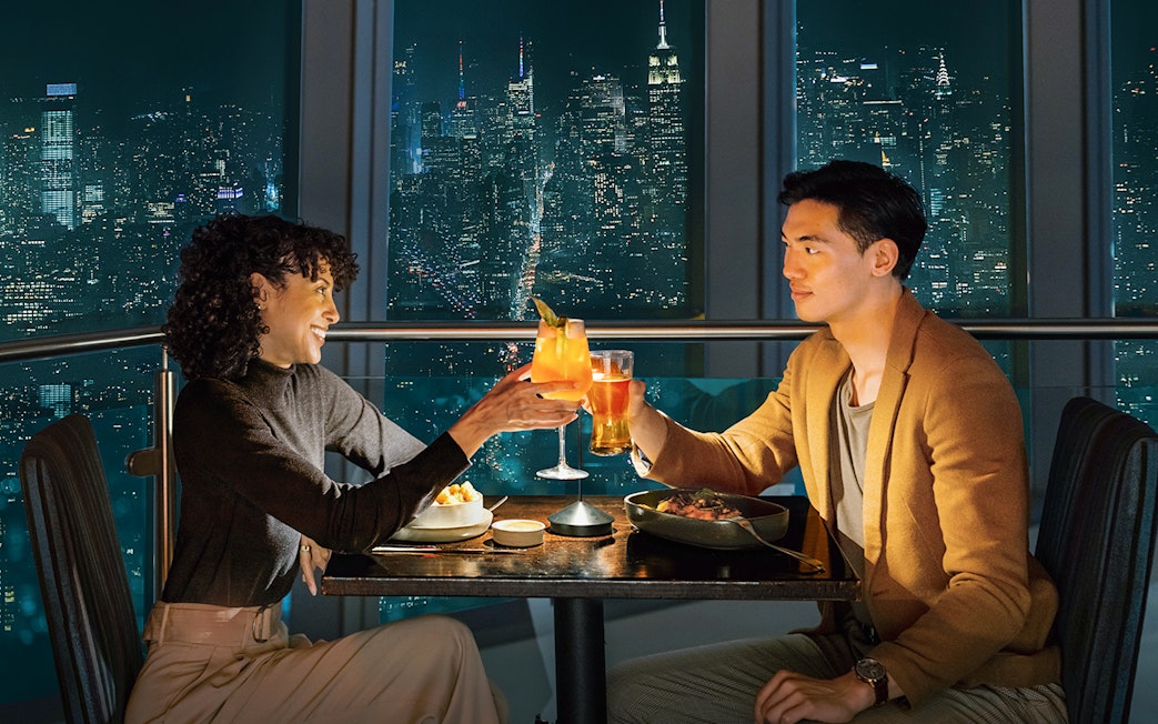 Couple dining with city skyline view at One World Observatory, New York City.