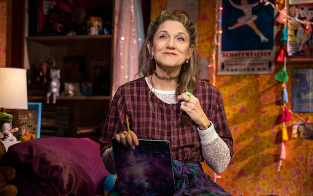 Person in a cozy room holding a pencil and notebook, related to Kimberly Akimbo.