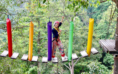 Woman crossing a colorful step bridge in a forest adventure park.