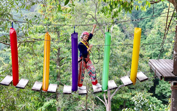 Woman crossing a step bridge over a lush green forest in Costa Rica.