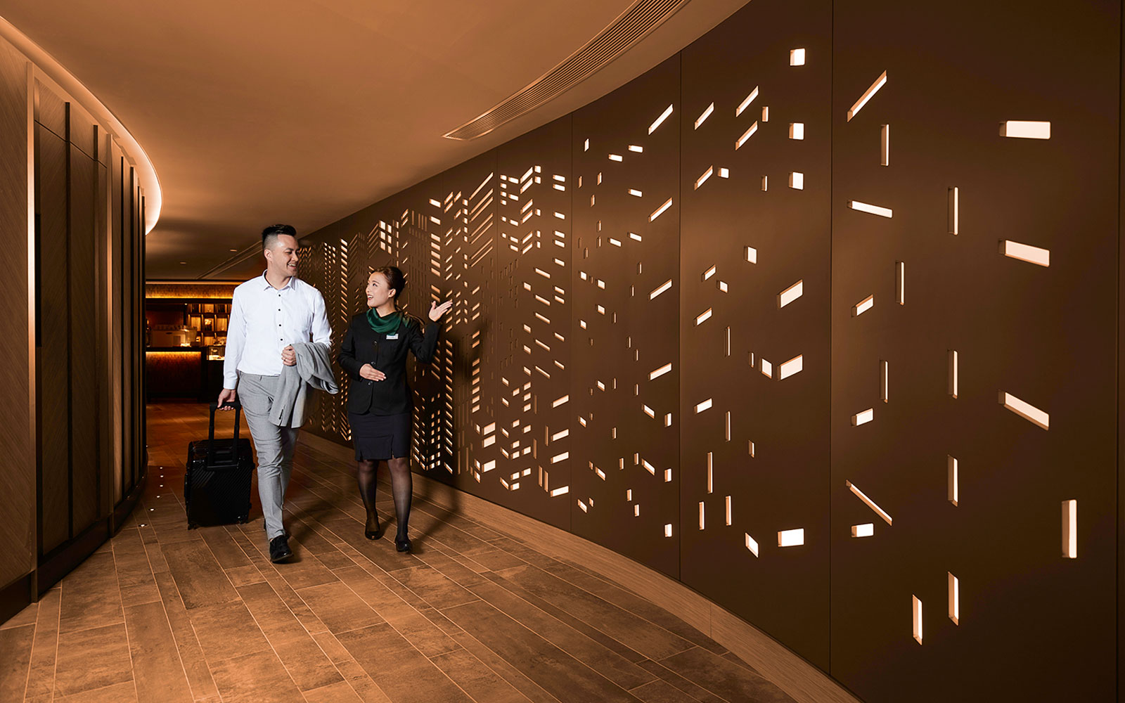 First-class lounge entrance at Hong Kong International Airport with a guest and staff member.