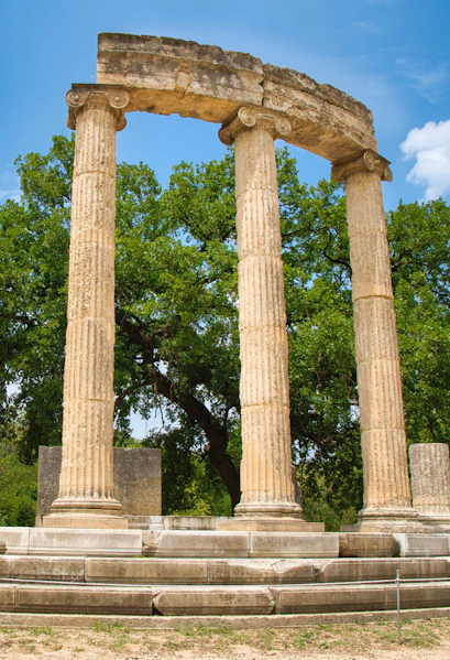 Ancient Olympia ruins with three standing columns in Greece.
