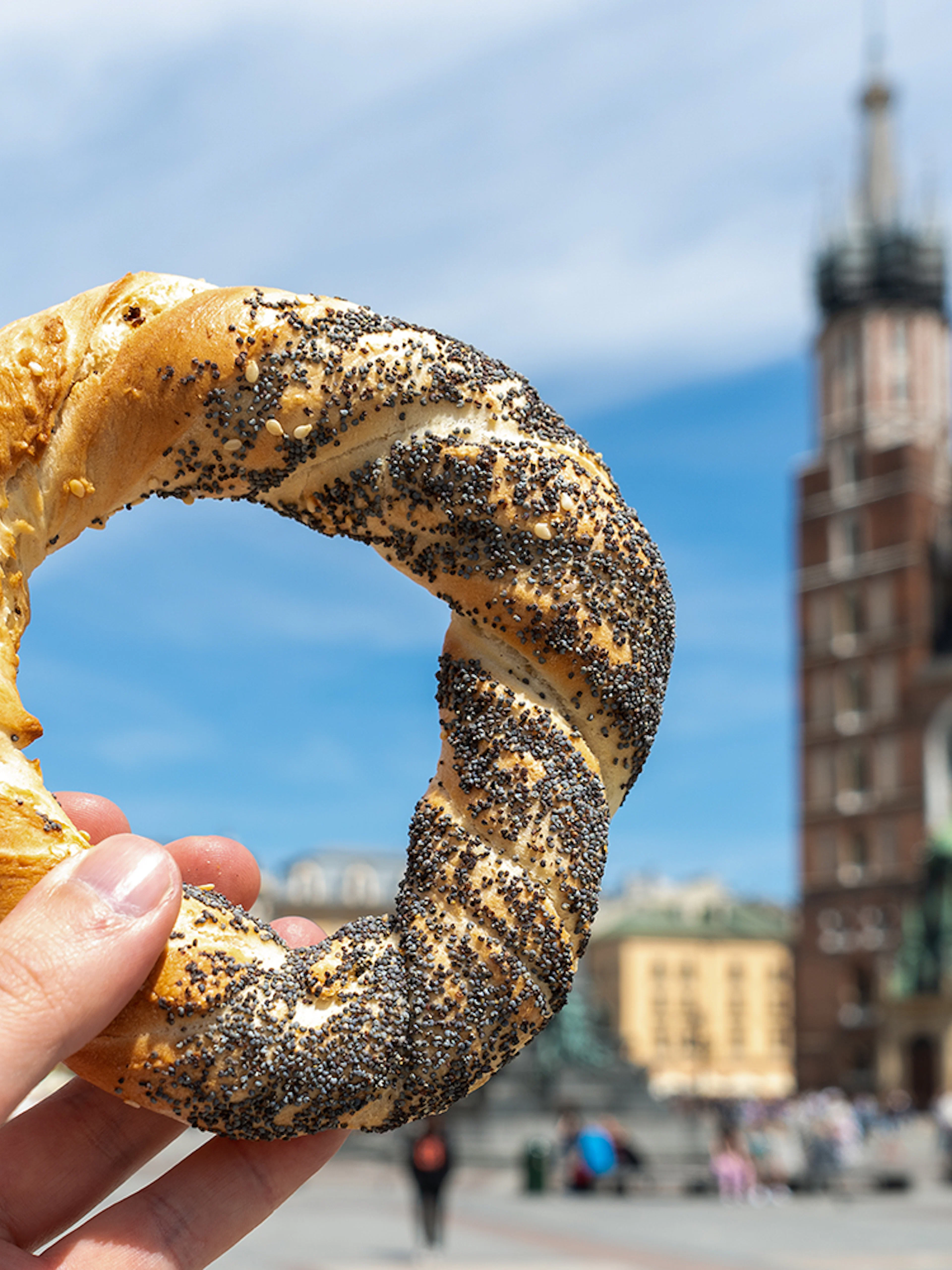 Kraków street food pretzel held in front of St. Mary's Basilica.