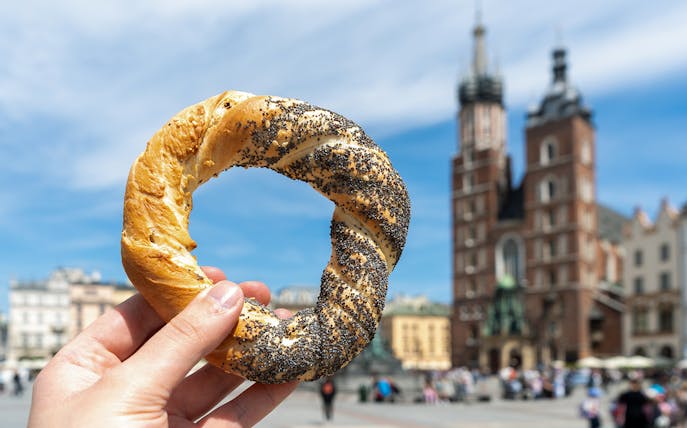 Kraków street food pretzel held in front of St. Mary's Basilica.