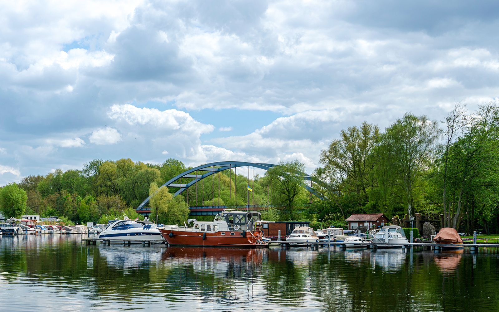 Boats docked near Konradshöhe Island with a bridge and lush trees in Berlin.