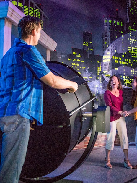 People interacting with a Bat-Signal exhibit at Madame Tussauds Orlando, included in the Orlando Explorer Pass.