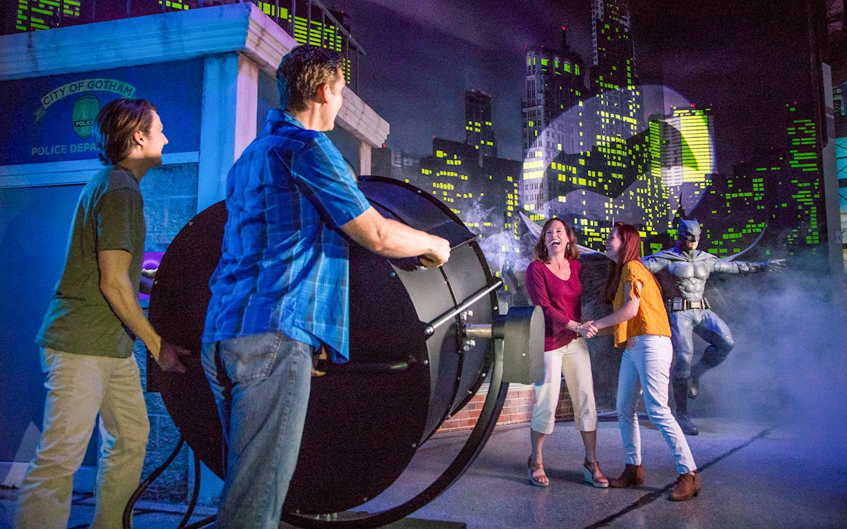 People interacting with a Bat-Signal exhibit at Madame Tussauds Orlando, included in the Orlando Explorer Pass.